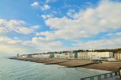 Buildings by sea against sky