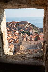 Aerial view of townscape by sea against sky