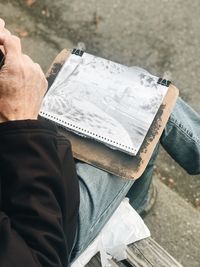 Low section of man with painting sitting outdoors