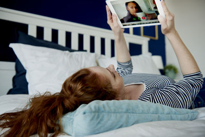 Rear view of woman relaxing on bed at home