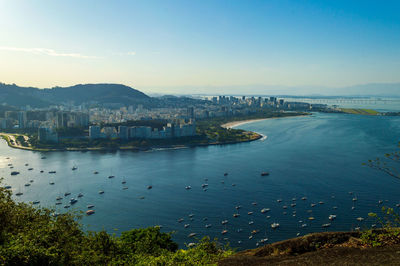 High angle view of city by sea against sky