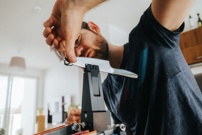 Midsection of man sharpening knife at home