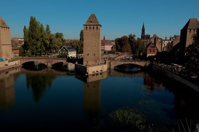 Arch bridge over river by buildings against sky