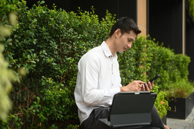 Young man using laptop while sitting at park