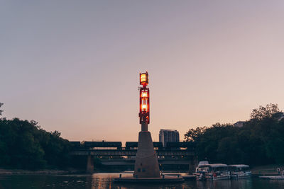 Built structure by river against clear sky at sunset