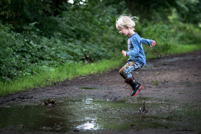 Side view full length of girl playing in puddle