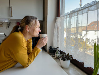 Woman is holding a cup and smelling the drink
