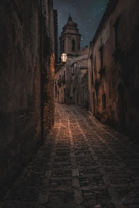 Narrow alley amidst buildings in city at night