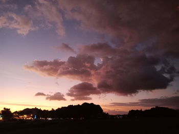 Low angle view of silhouette trees against dramatic sky