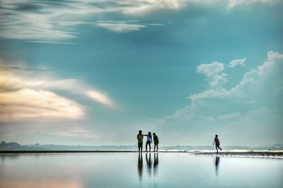 Friends standing at beach against sky