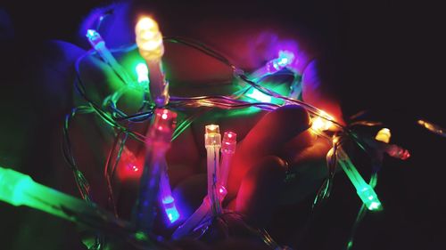 Close-up of human hand holding colorful illuminated lighting equipment