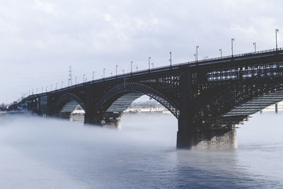 Arch bridge over river against sky