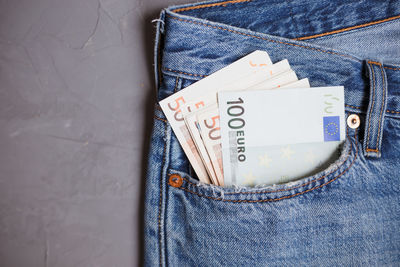 Directly above shot of paper currencies in jeans pocket on gray background