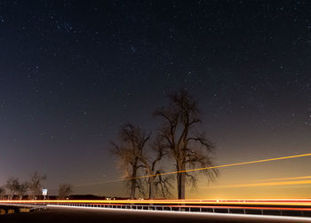 Light trails on street against star field at night