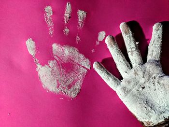 Close-up of hand over pink background