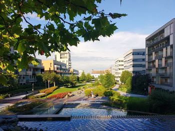 Buildings by swimming pool in city against sky