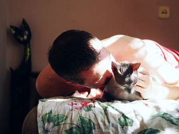 Close-up of man with cat on bed at home