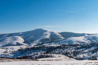 Scenic view of snowcapped mountains against clear blue sky