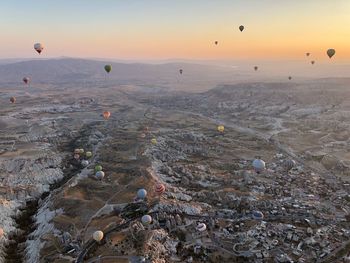 Aerial view of hot air balloons flying over landscape during sunset