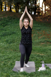 The relaxed girl is doing yoga in the park on carpet