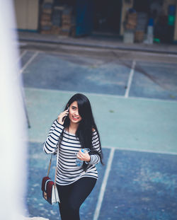 High angle view of young woman talking on phone while walking on steps
