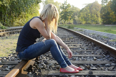 Depressed woman sitting on railroad track