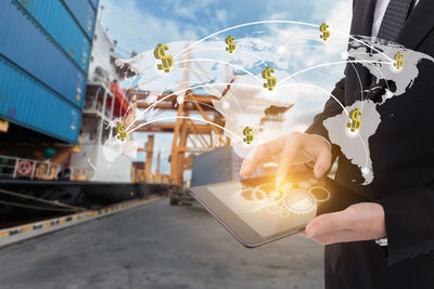 Digital composite image of businessman using digital tablet with icons at commercial dock