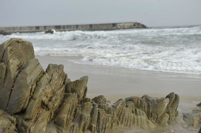 Rock formation at beach against sky