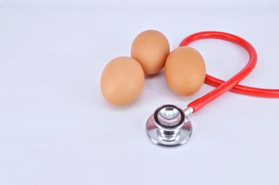 High angle view of eggs and stethoscope on white background