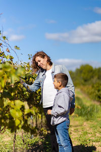 Mother and son looking grapes on a vineyard