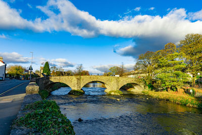 Arch bridge over river against sky