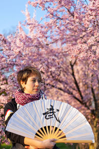 Young caucasian woman posing a wushu martial art posture in a sunny day, a pink tree in background