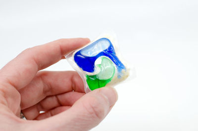 Close-up of hand holding plastic against white background