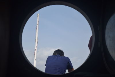 Rear view of man on airplane against sky