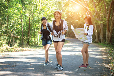 Full length of woman and women walking on road against trees