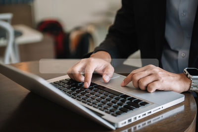 Midsection of businessman using laptop on table