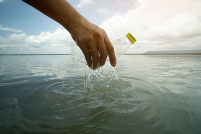 Midsection of person holding sea against sky