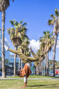 Woman doing handstand on grass against sky