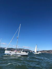 Sailboats sailing in sea against clear blue sky