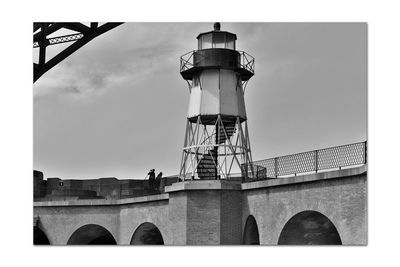 Low angle view of lighthouse by building against sky