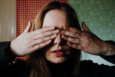 Close-up portrait of woman covering face with hand