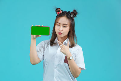 Young woman using mobile phone against blue background