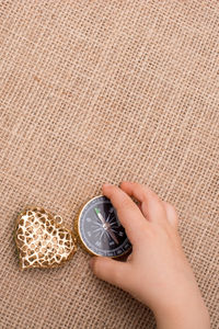 Close-up of hand holding navigational compass by heart shape