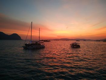 Sailboats in sea against romantic sky at sunset