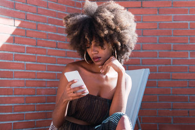 Attractive african american woman checking social media holding smartphone outdoors. 