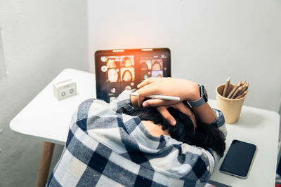 Midsection of man using mobile phone on table against wall