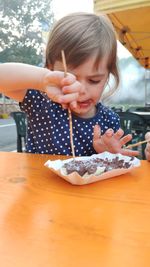 Portrait of cute girl holding table