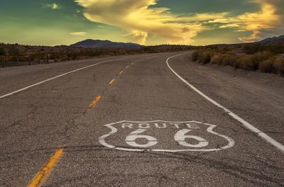 Text on road against sky during sunset