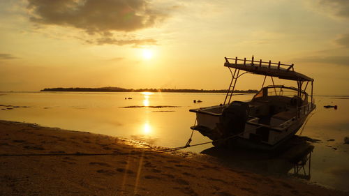 Boat moored at beach against sky during sunset