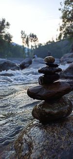 Stack of stones in water against sky